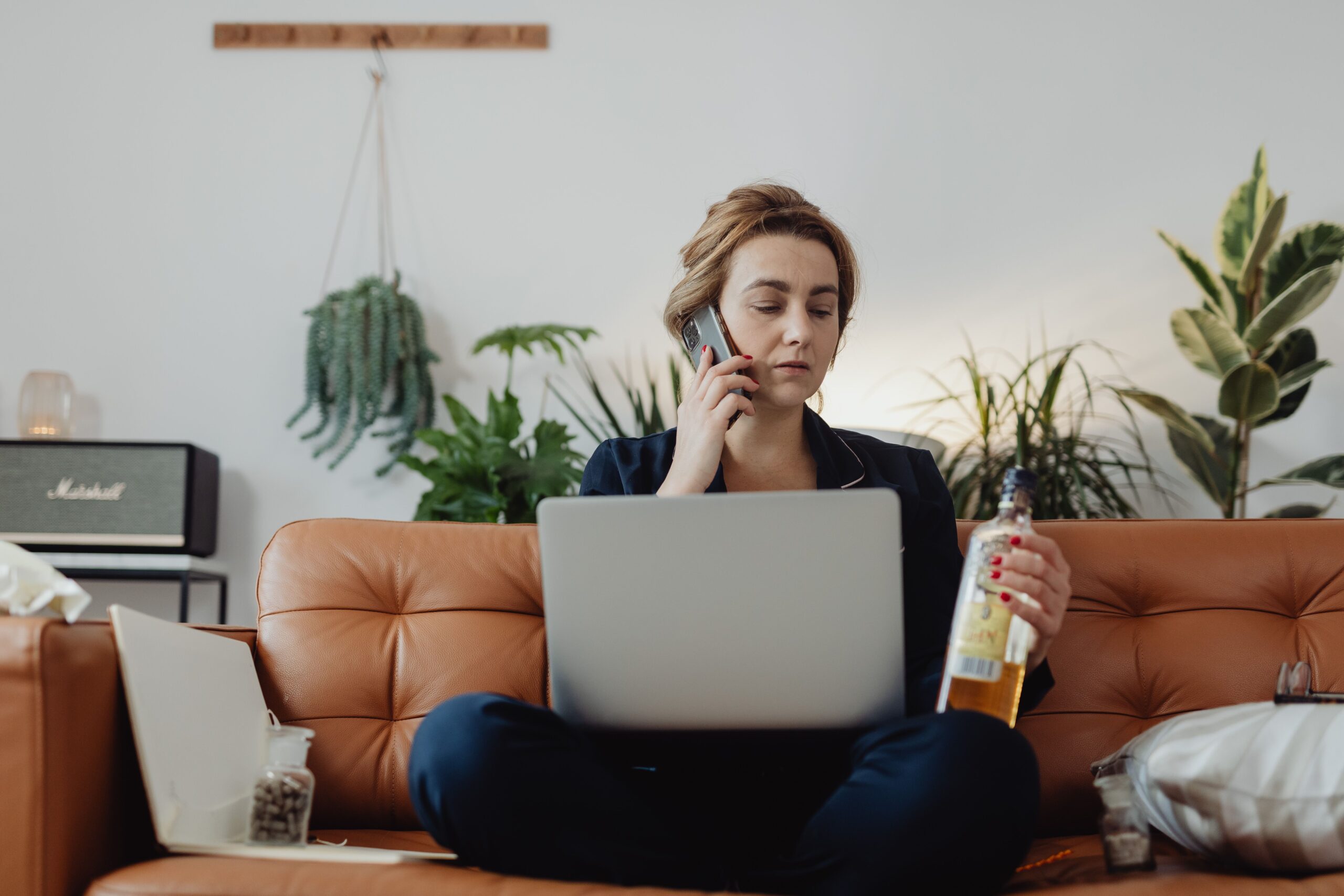 Woman on couch with laptop and alcohol, discussing workplace A&D policies