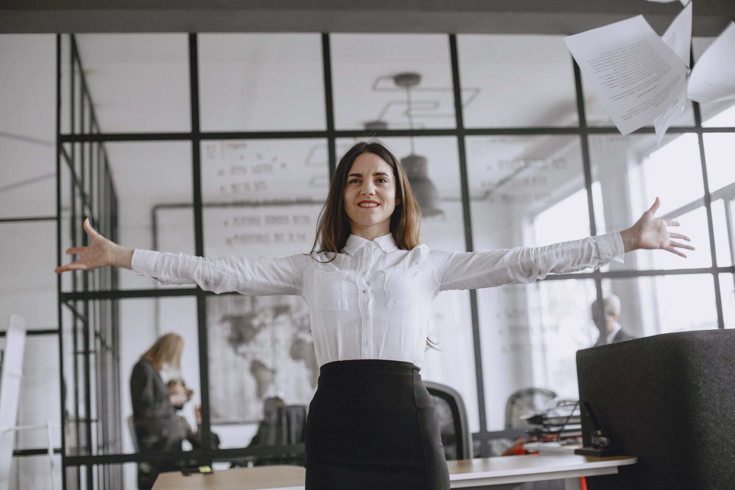 Woman celebrating policy review and updating, throwing papers in office