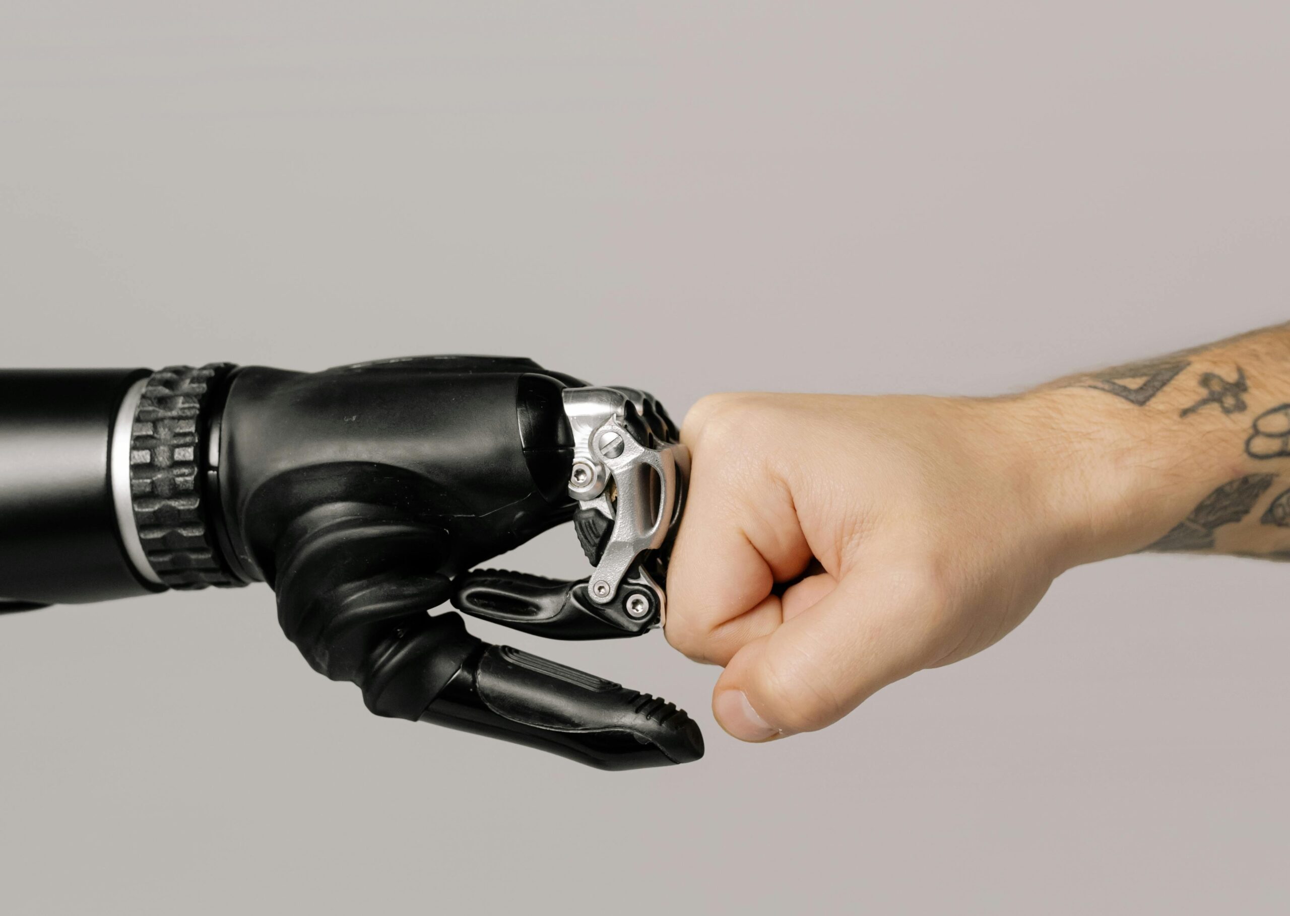 Human fist bumps prosthetic hand, symbolizing AI policy integration.