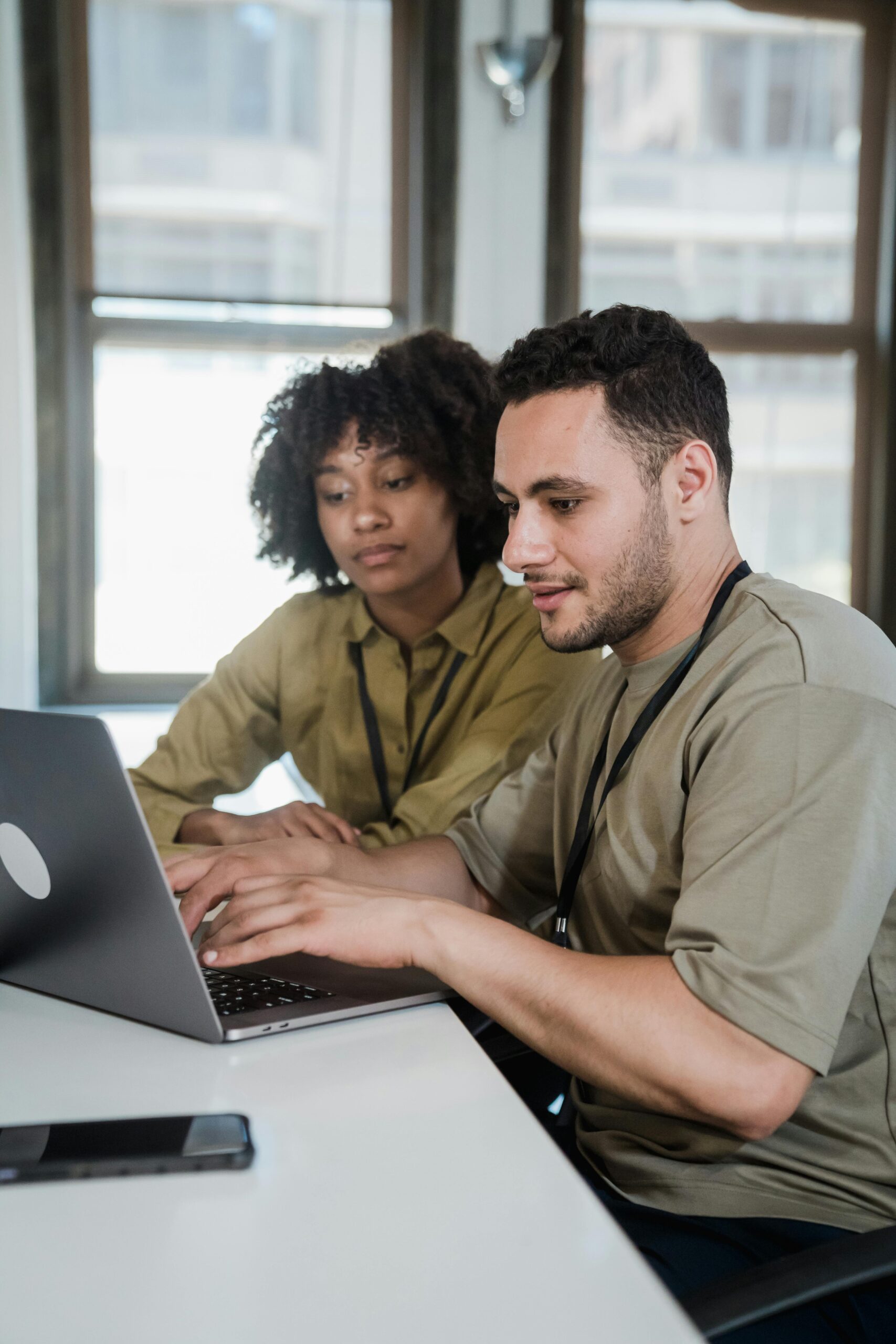 Colleagues review a policy handbook on a laptop, discussing remote and hybrid work.