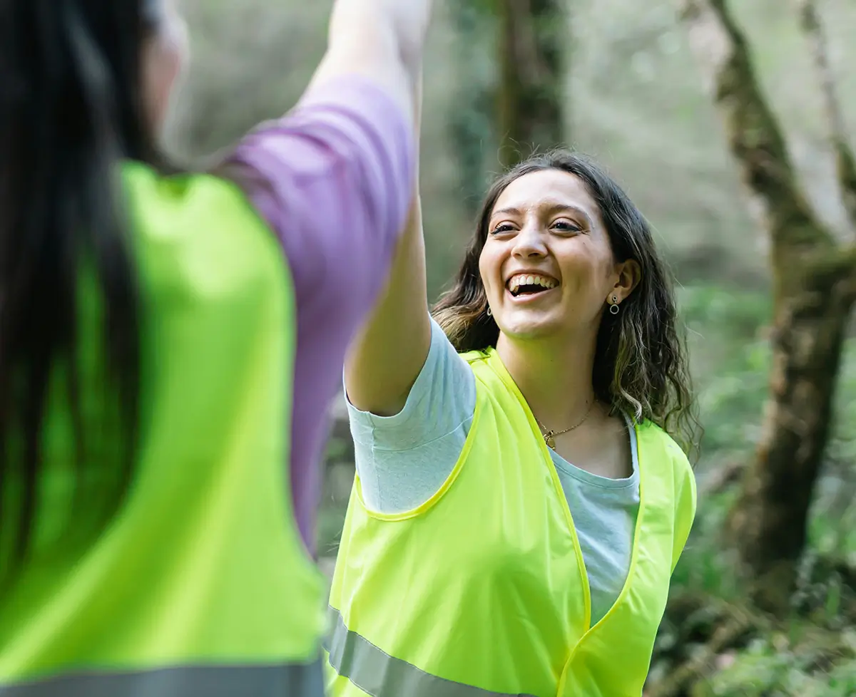 Outdoor worker in high-vis vest is giving a high-five to another worker