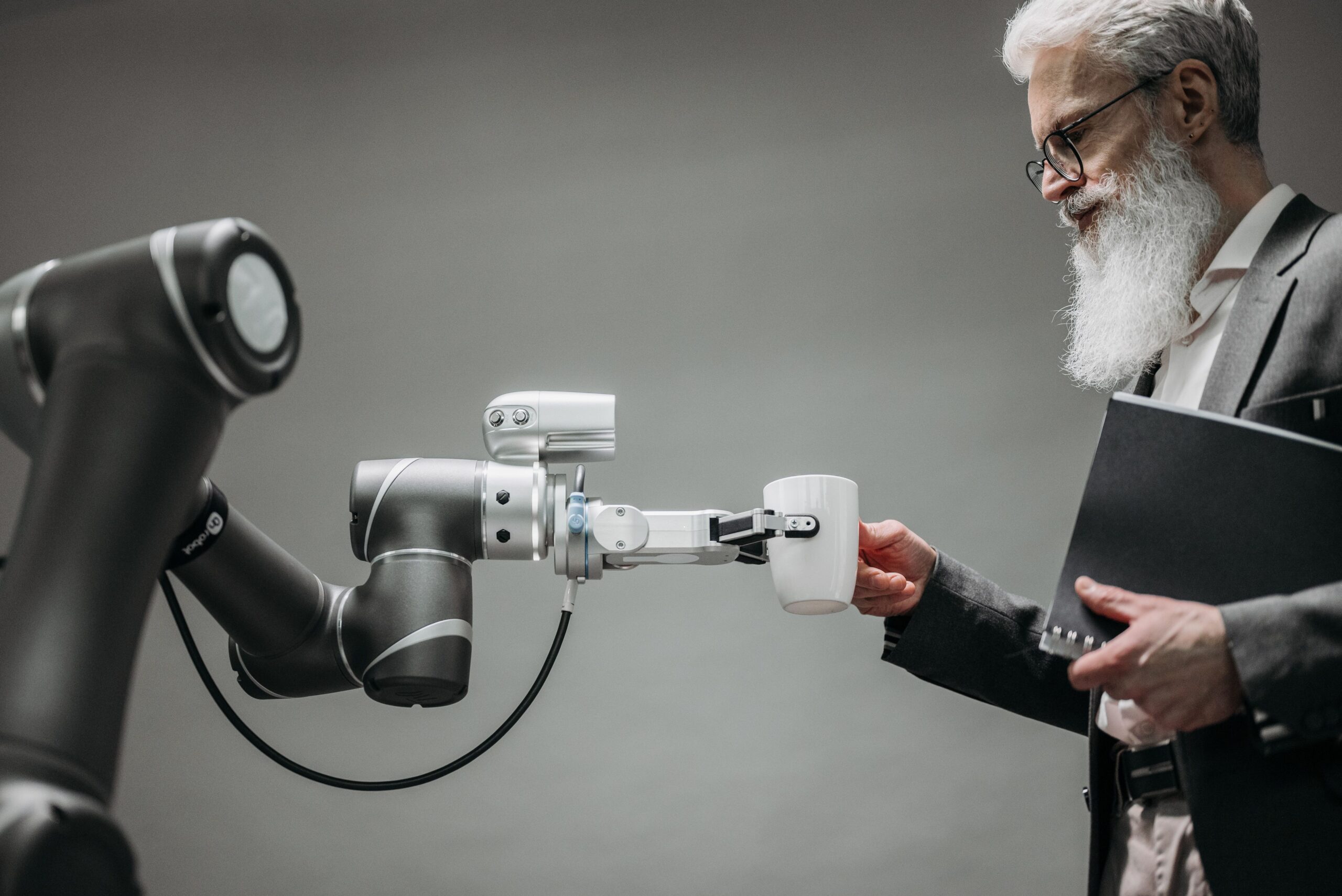 Man in suit receives coffee from robot arm, illustrating AI in hybrid work for NGOs.
