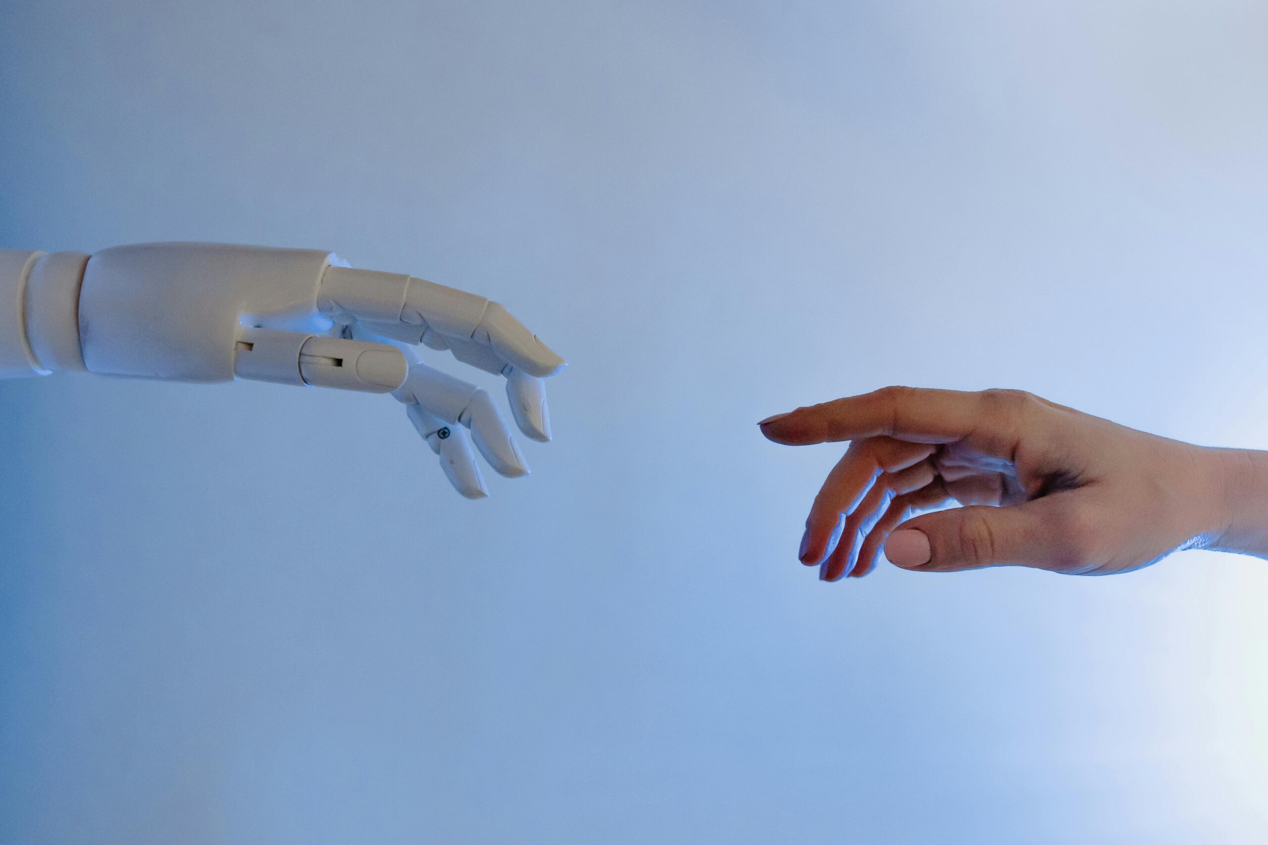 Robotic hand and human hand reaching out, symbolizing AI and human collaboration for responsible AI governance.