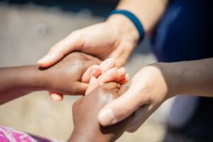 Hands of different skin tones clasped together, symbolizing unity in social services.